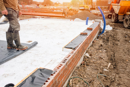 Builder placing polystyrene insulation boards on waterproofing membrane during floor construction. energy saving conceptの写真素材