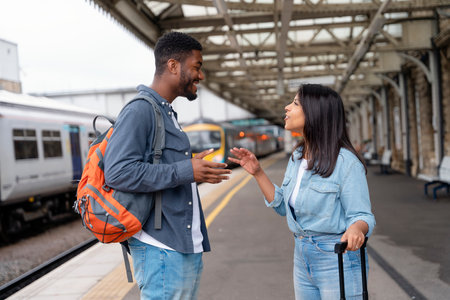 Happy man and woman in love waiting for a train and talking at a railway station platformの写真素材