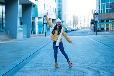 smiling young woman having fun time, using mobile phones outdoor in an urban winter city. people, communication, shopping and lifestyle conceptの写真素材