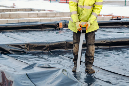 Waterproof installation at new house construction. Builders installing underfloor waterproof membrane during new house constructionの写真素材