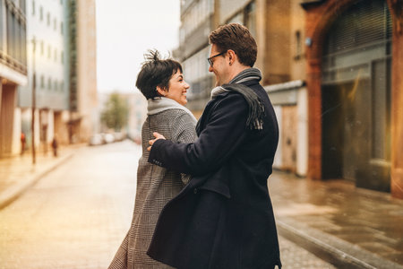 Handsome man and beautiful woman couple falling in love, hugging each other, dancing as they walk around city, having a fun time, lifestyle photoの写真素材