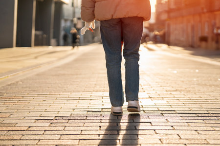 legs of young woman student walking along paved street in city at sunsetの写真素材