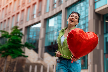 joyful woman with heart-shaped balloon falling in love walking around the city. Lifestyle peopleの写真素材