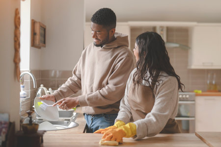 man helping woman cleaning kitchen washing dishes together at home toned imageの写真素材