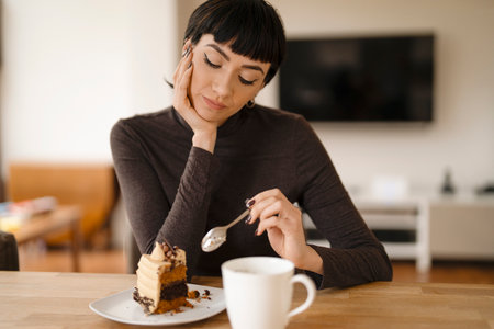thinking woman eating chocolate cake and drinking hot drinkの写真素材