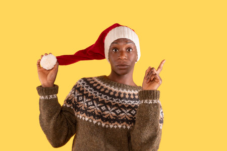 surprised Christmas woman in Santa hat pointing up index finger on yellow backgroundの写真素材
