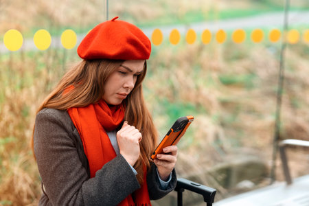 focused woman using phone at bus tram stopの写真素材