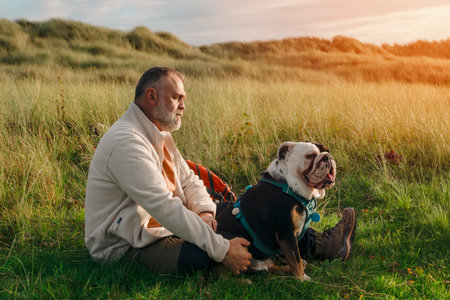 serene pensioner with English bulldog resting on grass in Wales seaside Happy Free time in retirementの写真素材