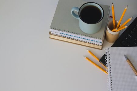 Top view on modern creative student workspace. Blue cup of coffee, yellow pencils on reusable paper tube on white table. Home office of a creative entrepreneur. Banner with copy space.の写真素材