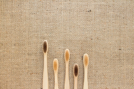 Top view on set of natural bamboo toothbrushes on rustic burlap background with copy space....