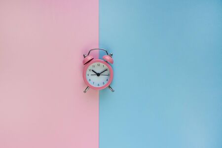 Ringing twin bell vintage alarm clock isolated on pink and blue background with copy space. Rest hours time, goodmorning, new life time.の写真素材