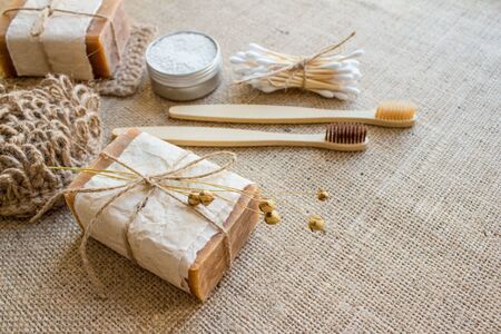 Set of natural bathroom and home spa tools. Sustainable zero waste and lifestyle concept. Ecotolls toothbrushes, bamboo swabs, soap, dry shampoo, toothpowder on fabric background with copy spaceの写真素材