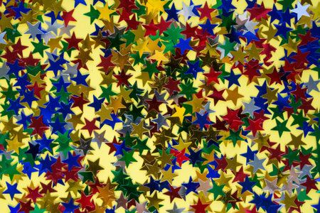 Colorful star shaped sparkles on yellow as the best background for your creative design with copy...