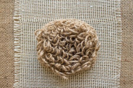 Close up of natural hand made jute washcloth for washing dishes or body, for dry anti cellulite massage. Top view on linen fabric, zero waste concept. Eco friendly gift ideas for home spaの写真素材