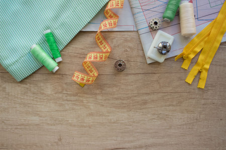 Horizontal composition with threads and sewing accessories and tools in green and yellow colours on...