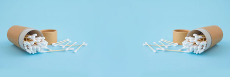Banner with bamboo cotton sticks in reusable paper packaging tube on trendy blue background....