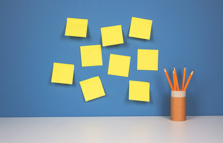 Yellow pencils in reusable paper packaging tube with yellow stickers on blue wall background with...