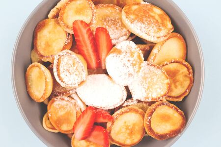 Close up of mini pancakes cereal with strawberries in blue bowl for breakfast as new trendy food activities during coronavirus quarantine lockdown, healthy breakfast for children before schoolの写真素材
