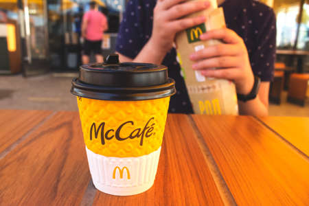 Lviv, Ukraine - June 13, 2020 : teenager boy having breakfast or lunch with coffe at McDonald's restaurant sitting at the wooden table, Weekday Breakfast Specialsのeditorial素材