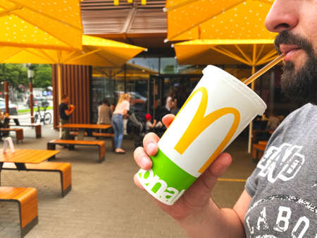 Lviv, Ukraine - June 15, 2020 : man drinking juice or cola during lunch at McDonald's restaurant, sitting on the open air terrace, selective focusのeditorial素材