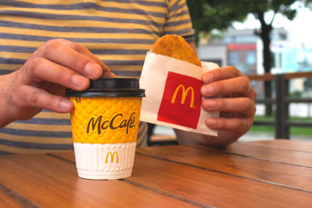 Lviv, Ukraine - June 14, 2020 : man having breakfast or lunch with coffe at McDonald's restaurant, sitting at the wooden table. Weekday Breakfast Specialsのeditorial素材