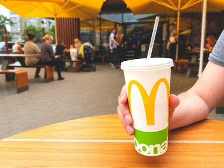 Lviv, Ukraine - June 15, 2020 : man drinking juice or coca-cola during lunch at McDonald's...