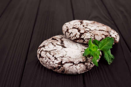 Close up of delicious chocolate cookies with fresh green mint topped with sugar, on black wooden background with copyspace for text or recipe - handmade gingersnap traditional cookies on rustic tableの写真素材