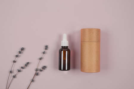 Dropper bottle with lavender essential oil and paper packaging tube on lilac background with copyspace for text. Mockup, home spa conceptの写真素材