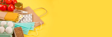 Closeup of food and medicaments donations with paper bag on yellow background with copyspace. Pasta,...