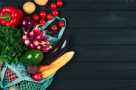 Cotton bag full of fresh farm raw vegetables from local farmer market, on black wooden background or...