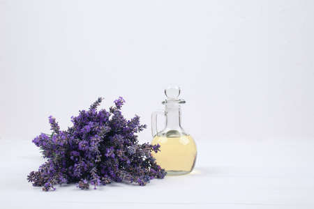 Mockup image of glass bottle with lavender essential oil and lavender flowers on white background with copyspace for text. Trendy toned photo for your blog or presentationの写真素材