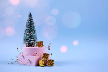 Trendy Christmas and New Year composition with Christmas tree, present boxes, decorations and bokeh lights on pastel blue background with copyspace. Selective focus, place for textの写真素材
