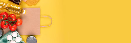 Banner with food donations on yellow background with copyspace - pasta, fresh vegatables, canned...