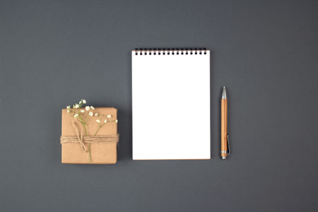Vintage flat lay composition with present box, blank copybook and wooden pen on grey background with...