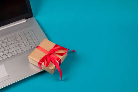 Front view on laptop computer and present box with red bow on green background with copyspace for your text. Seasonal sale, black friday and cyber monday. Online shopping and safe shopping conceptの写真素材