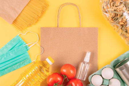 Food and medicaments donations with paper bag on yellow background with copyspace - pasta, fresh...