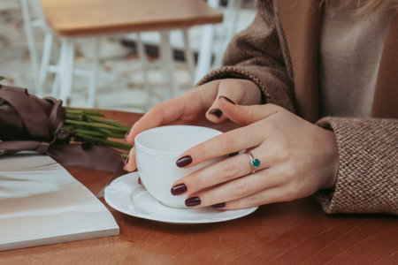 Faceless portrait of young stylish woman drinking morning coffee sitting on the openair cafe in the...