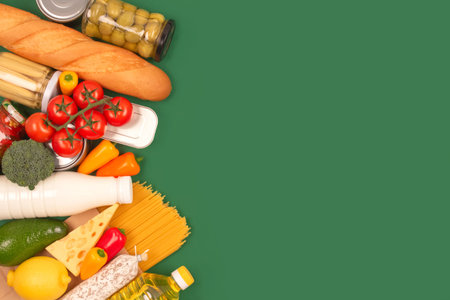 Different groceries or food donations on green background with copyspace - pasta, fresh vegatables,...