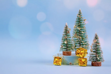 Christmas and New Year composition with New Year tree, golden present boxes, decorations and bokeh lights on pastel blue background with copyspace. Selective focus, place for your textの写真素材