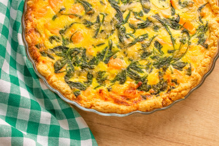 Seafood, salmon fish and baby spinach leaves quiche pie - homemade recipe pie on wooden table...