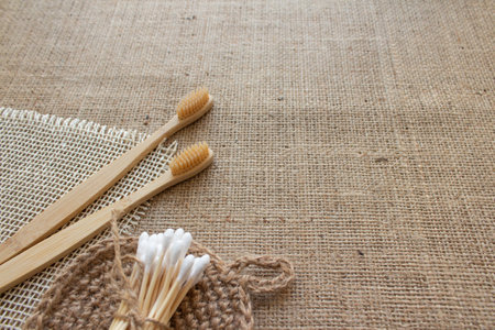 Natural bathroom tools, sustainable zero waste and lifestyle concept. Wooden toothbrushes, bamboo swabs, and handmade jute body washclothes on fabric background with copy space, mockupの写真素材