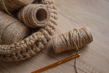 Making knitted baskets with linen or cannabis jute rolls on wooden table background with copy space. Handmade DIY and hobby concept, selective focusの写真素材