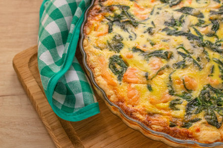 Close up view of salmon fish or seafood and spinach quiche pie - homemade recipe pie on wooden table background with copy space, selective focus. Top viewの写真素材
