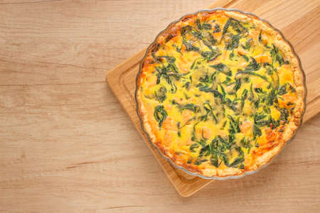 Seafood salmon fish and spinach leaves quiche pie - homemade recipe pie on wooden table background with copy space, selective focus. Top viewの写真素材