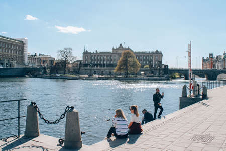Stockholm, Sweden - May 1, 2019 : Scenic sunny day panorama of Stockholm city center. Tourists and citizens enjoying sunny day at Stockholm quay, Gamla Stan. City tour concept. Selective focusのeditorial素材
