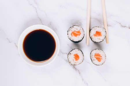Classic sashimi with salmon fish, soy sauce and chopsticks on white marble background - maki sushi roll, nori maki, futomaki. Asian food delivery, sushi bar menu, online home order food conceptの写真素材