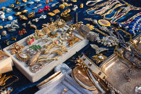 Antiques on flea market or seasonal festival - vintage jewelry, silver brooches and other vintage things. Collectibles memorabilia and garage sale concept, selective focusの写真素材