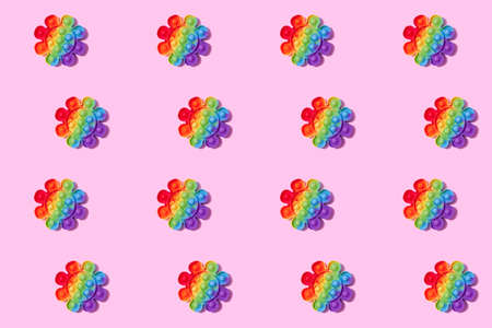 Pattern made with rainbow pop it fidget toy on pink background. Push bubble fidget sensory toy - washable and reusable stress relief toy. Antistress toy for children or adult. Mental health conceptの写真素材