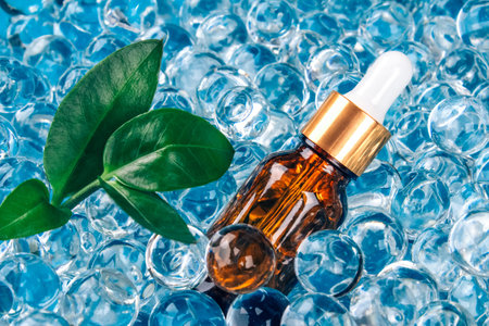 Mockup dropper bottle with natural organic herbal cosmetic oil on blue background of water gel...