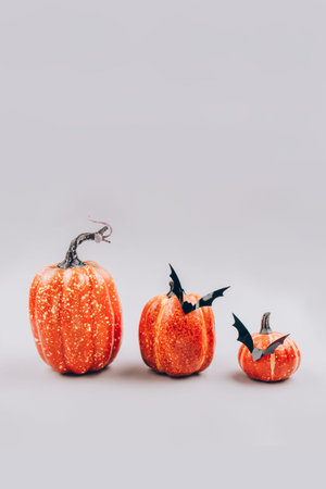 Vertical image, minimal Halloween scary and concept. Decorative orange pumpkins with bats on light...